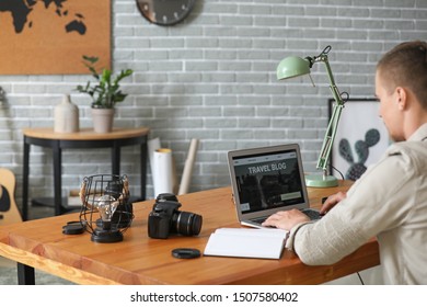 Male Travel Blogger With Laptop At Table