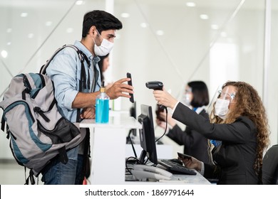 Male traveler shows phone to female officer at airline check in counter for issue airplane ticket boarding pass. Woman staff wear face mask to prevent from coronavirus pandemic. New normal lifestyle
