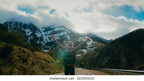 Male traveler walk on empty mountain road with rise hands and hiker backpack. Men feeling freedom on vacation trip.  - Powered by Shutterstock