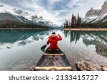 Male traveler in winter coat canoeing in Spirit Island on Maligne Lake at Jasper national park, AB, Canada