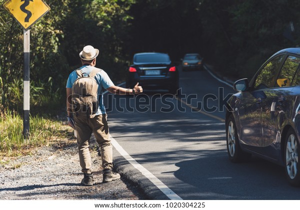 Male travelers are requesting a passing car\
to reach a distant\
destination.