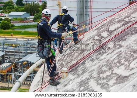 Male two worker inspection wearing safety first harness rope safety line working at a high place on tank roof spherical gas propane.