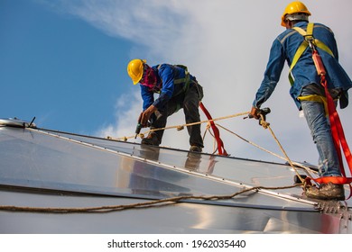 Male two workers rope access height safety connecting with a knot safety clipping into roof fall arrest and fall restraint anchor point systems ready to ascending, construction site oil tank dome. - Shutterstock ID 1962035440