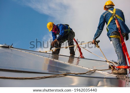 Male two workers rope access height safety connecting with a knot safety clipping into roof fall arrest and fall restraint anchor point systems ready to ascending, construction site oil tank dome.