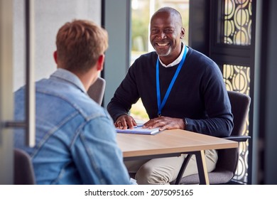 Male University Or College Student Having Individual Meeting With Tutor Or Counsellor