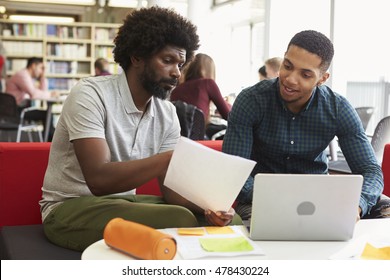 Male University Student Working In Library With Tutor