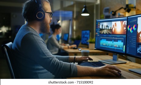 Male Videographer Edits and Cuts Footage and Sound on His Personal Computer, Puts on His Monitors/ Headphones. His Office is Modern and Creative Loft Studio. - Shutterstock ID 715100092