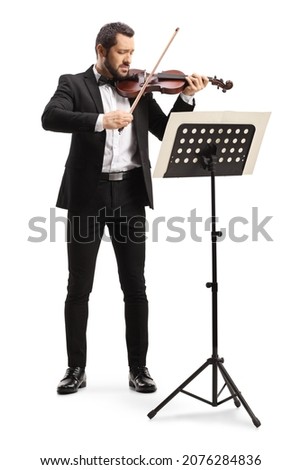 Male violinist playing a violin in front of a sheet music stand isolated on white background 