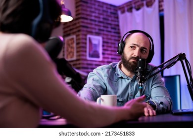 Male vlogger interviewing person on podcast discussion, talking to guest in studio. Young man having conversation with social media blogger, recording show for channel content.