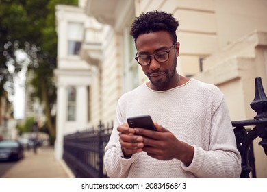 Male Vlogger Or Social Influencer In City Using Mobile Phone On Street To Post To Social Media