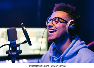 Male vocal artist, singer, podcaster with curly hair, headphones in sound studio recording new melody or album. - Powered by Shutterstock