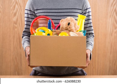 Male volunteer holding donation box with old toys.