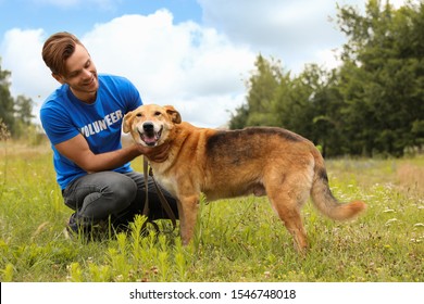 Male Volunteer With Homeless Dog At Animal Shelter Outdoors