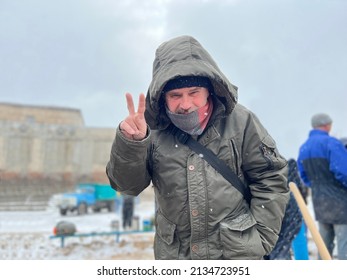 Male Volunteer Shows Sign Of Victory While Filling Sandbags At Barricades On Streets Of City Of Ukraine.  War