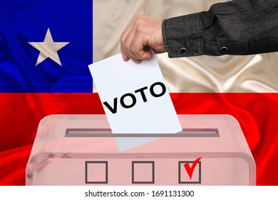 Male Voter Drops A Ballot In A Transparent Ballot Box On The Background Of The National Flag Of Chile, Vote In Spanish, Concept Of State Elections, Referendum