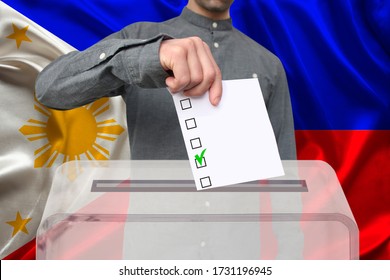 male voter drops a ballot in a transparent ballot box against the background of the philippines national flag, concept of state elections, referendum - Shutterstock ID 1731196945