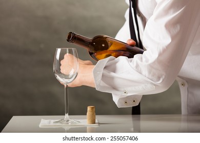 Male Waiter Or Butler Serving Pouring Wine Into Glass.