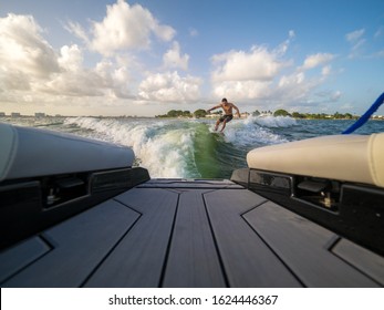 Male Wake Surfing Wave Behind Boat At Sea