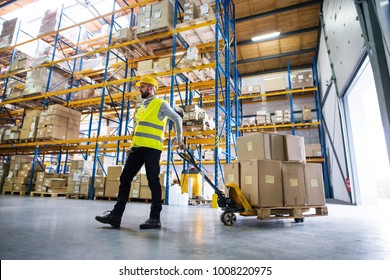 Male Warehouse Worker Pulling A Pallet Truck.