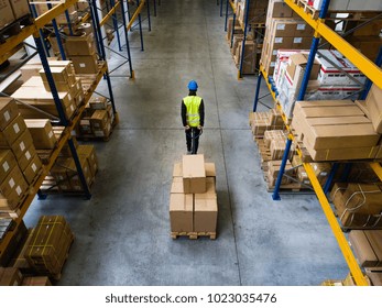 Male Warehouse Worker Pulling A Pallet Truck.