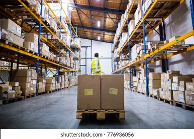 Male Warehouse Worker Pulling A Pallet Truck.