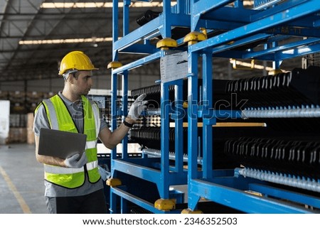 Male warehouse worker wearing safety uniform working with laptop computer and inspecting quality for auto spare parts on shelves for packaging in packaging department at warehouse storage