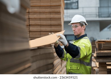 Male warehouse worker working and inspecting quality of cardboard in corrugated carton boxes warehouse storage - Powered by Shutterstock