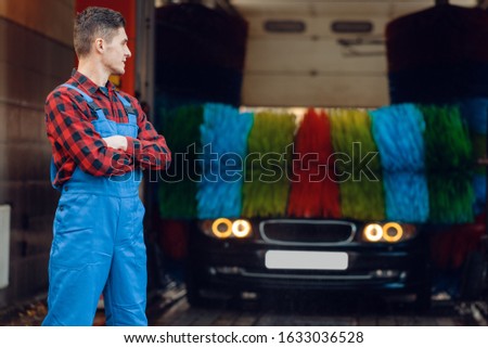 Male washer in uniform on automatic car wash