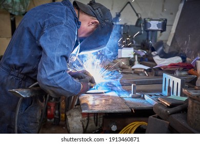 Male Welder At Work At A Metal Fabrication Workshop Welding A Plate Onto A Metal Section