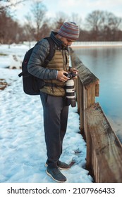 Male Wildlife Photographer In Park Taking Photo During Winter Time With Blue Sky And Snow On The Ground With Camouflage Clothes