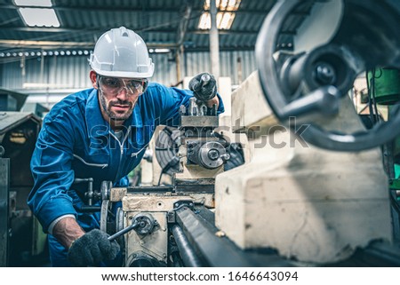 Male worker in blue jumpsuit and white hardhat operating lathe machine.  商業照片 © 