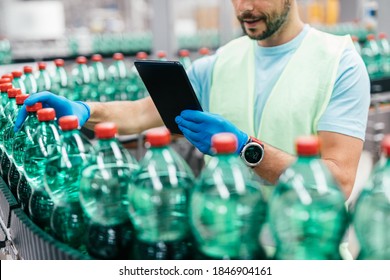 Male worker in bottling factory checking water ottles before shipment. Inspection quality control. 