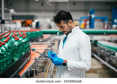 Male worker in bottling factory checking water bottles before shipment. Inspection quality control. 