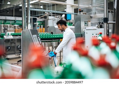 Male worker in bottling factory checking water bottles before shipment. Inspection quality control. 