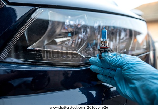 male worker changes light bulb in the headlight,\
auto repair and service\
concept