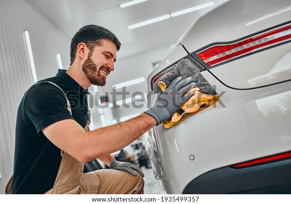 Male worker cleaning automobile\
with rag. Car detailing and car wash concept. Close up\
view.