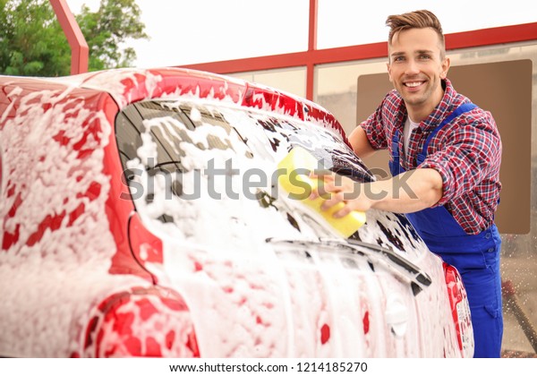 Male\
worker cleaning vehicle with sponge at car\
wash