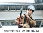 Male worker climbing up scaffolding at a construction site to work at height