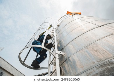 Male worker climbs up the ladder inspection stainless tank work at height safety - Powered by Shutterstock