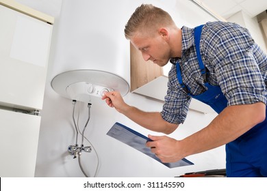 Male Worker With Clipboard Adjusting Temperature Of Water Heater