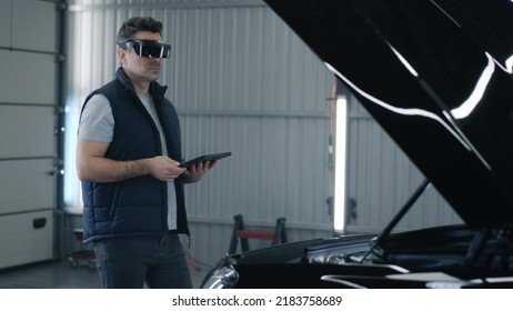 A male worker diagnosing and checking a car after a repairing in a car service using a tablet and a modern virtual reality glasses - Powered by Shutterstock