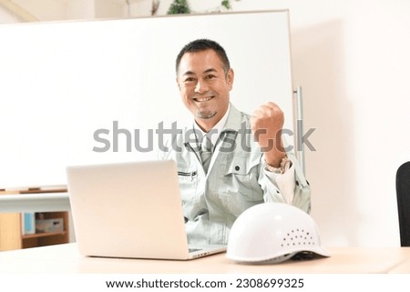 A male worker doing a guts pose in front of a PC
