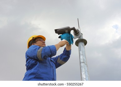 A male worker doing a maintenance work by cleaning and inspecting security camera.