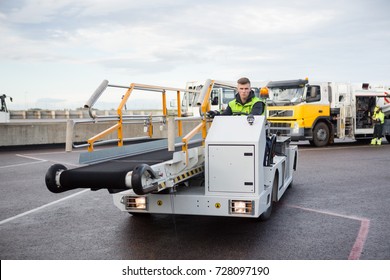 Male Worker Driving Luggage Conveyor Truck On Airport Runway