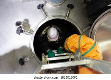 The male worker enters the tank fitted with a ventilation system during the work - Shutterstock ID 1813016092