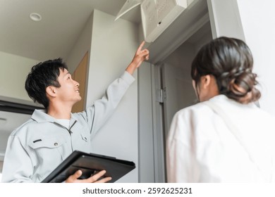 A male worker explaining about the distribution board and breakers and a housewife listening to the explanation
