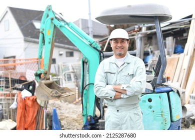 Male Worker Folding His Arms In Front Of Heavy Machinery At The Construction Site