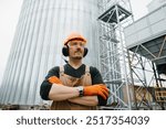 A male worker, in front of grain silos.