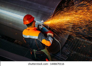 Male worker grinding butt weld pipe in metalwork workshop. 