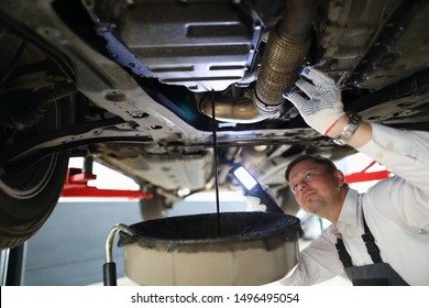 Male Worker Holding In Hands Electric Torch Inspecting Oil Leak Under Car Portrait. Auto Occupation Concept